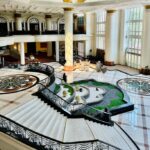 The lobby of a hotel with a large marble staircase